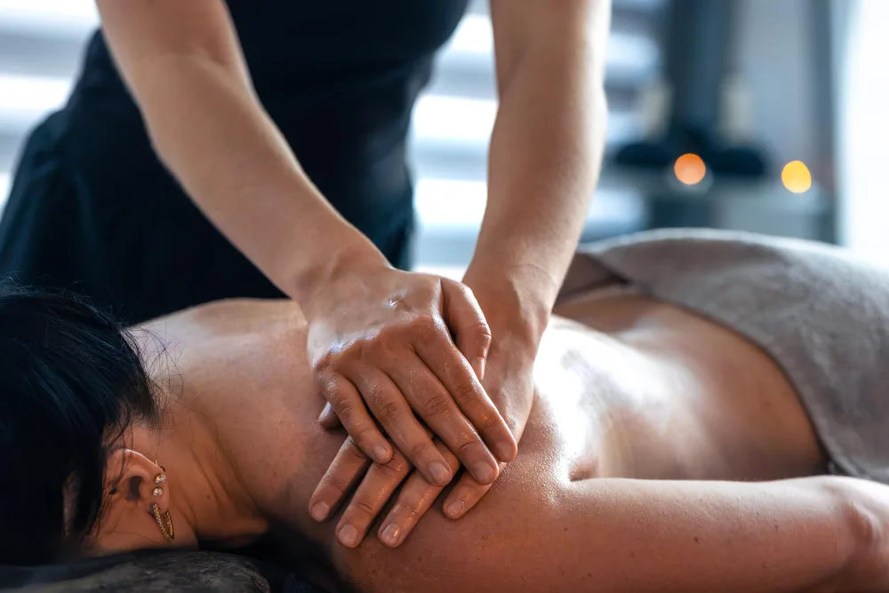 Gestes de massage sur le haut du dos dans une atmosphère de détente